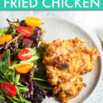a piece of fried chicken on a plate with a salad on the side