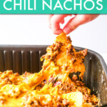 A child's hand pulling cheesy nachos out of an air fryer basket