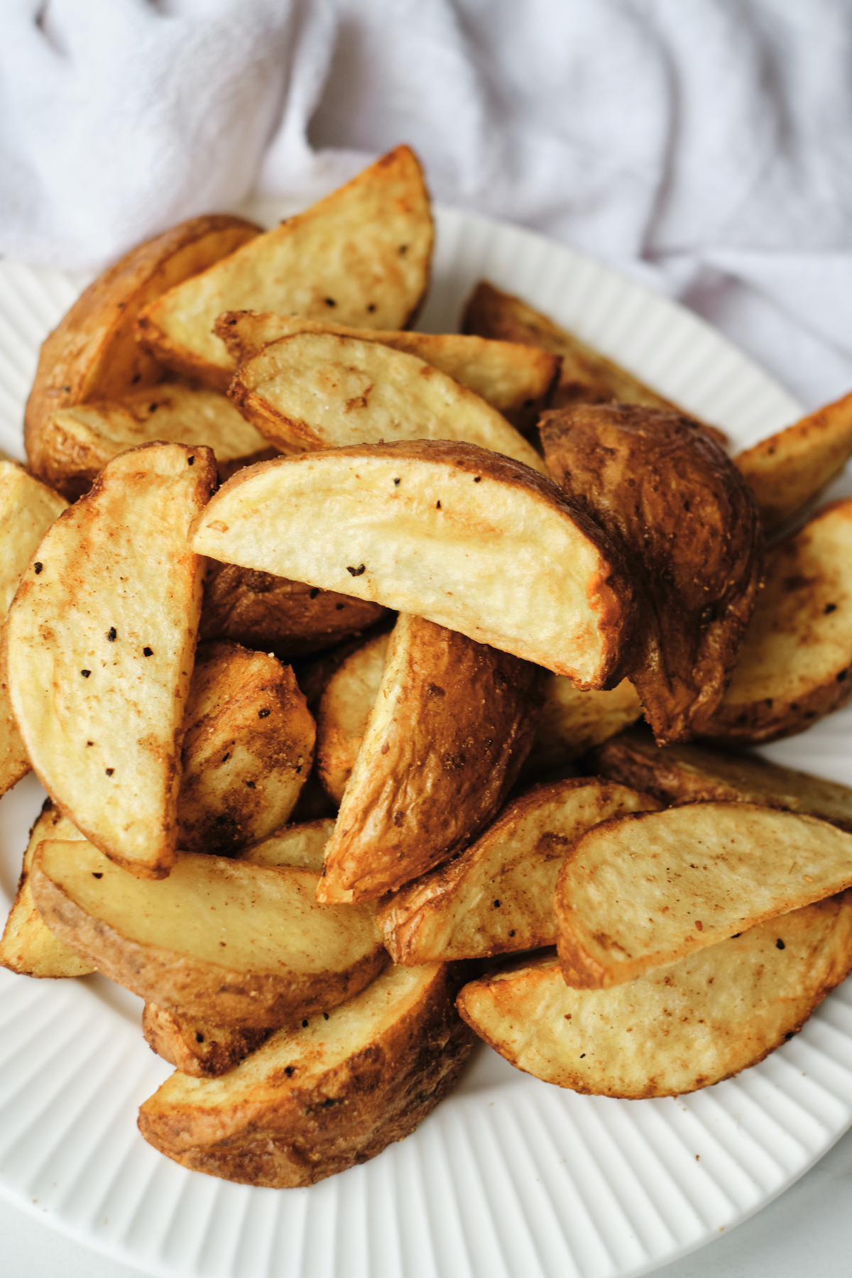 close up view of the completed air fryer potato wedges served on a white plate