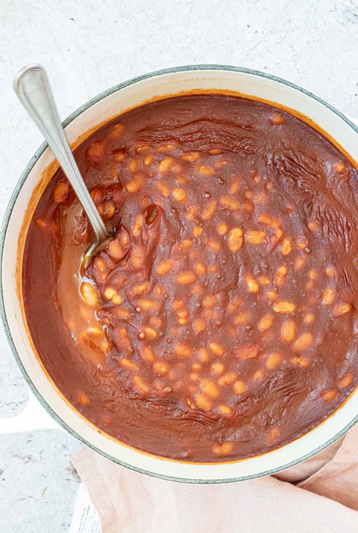 a pot filled with canned baked beans with a serving spoon.