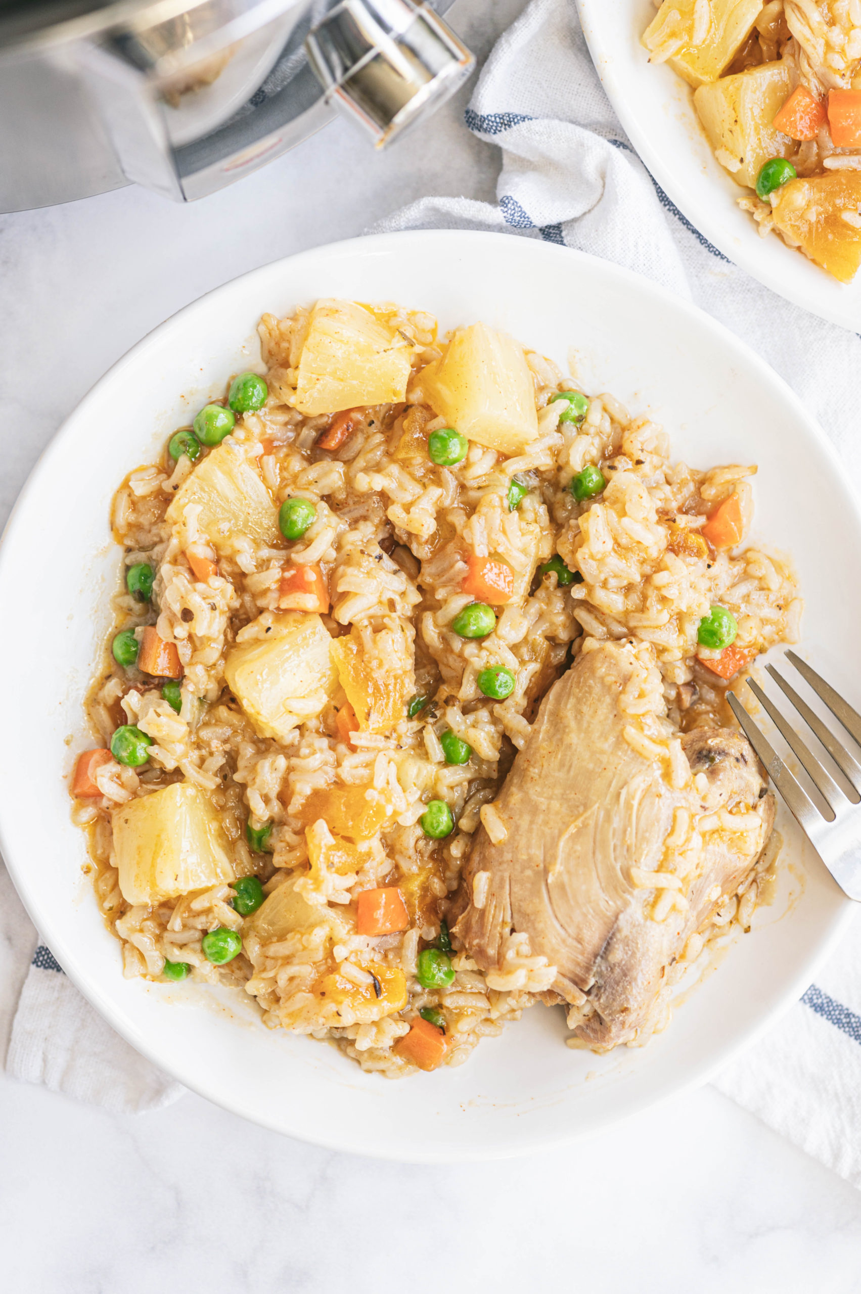 the finished instant pot chicken and rice served on a white plate and next to the instant pot