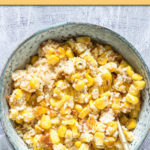 a round bowl of scalloped corn with a spoon in it