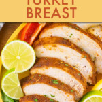 A sliced turkey breast on a plate garnished iwth lime wedges and vegetables