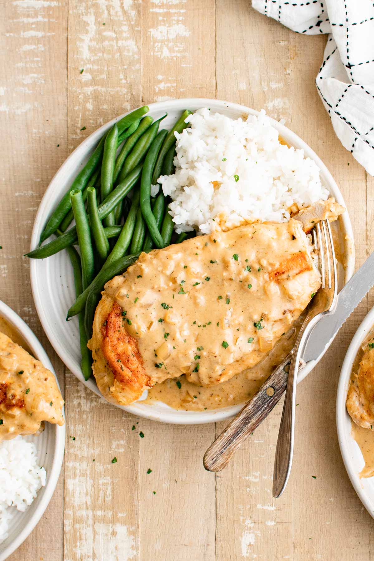 a plate of smothered chicken served with green beans and mashed potatoes